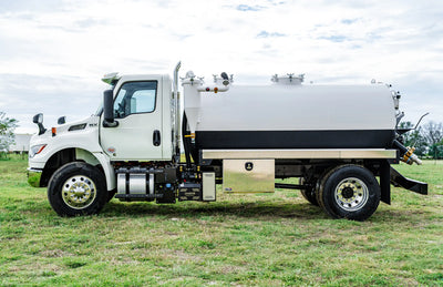 Driver-side profile image of a 2026 International MV-607 Vacuum Truck for sale, equipped with a 1900 Gallon Carbon Steel Tank parked in a grassy field | Arkson Truck Co