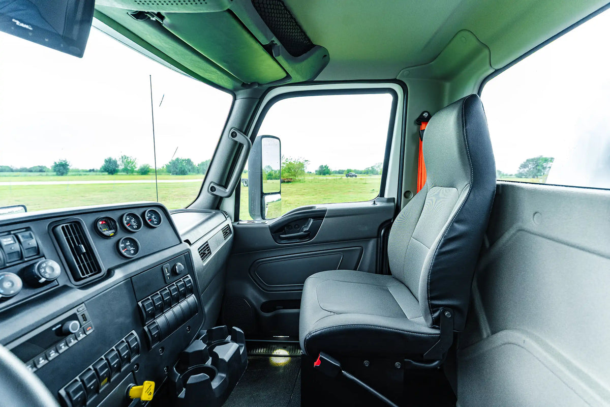 Close-up of the passenger-side interior truck cab of the 2026 International MV-607 2500 Gallon Vacuum Truck for sale from Arkson Truck Co, showing the passenger's seat, cup holders, dashboard, and various control switches and gauges.