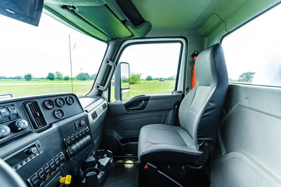 Close-up of the passenger-side interior truck cab of the 2026 International MV-607 2500 Gallon Vacuum Truck for sale from Arkson Truck Co, showing the passenger's seat, cup holders, dashboard, and various control switches and gauges.